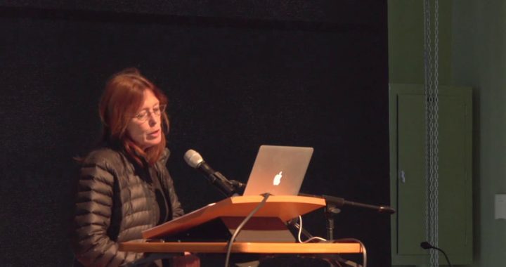 Carla Freccero is shown giving a talk, with a laptop and microphone.