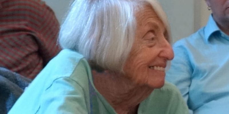 A cropped photo of Helene Moglen in profile, leaning forward and smiling while listening.